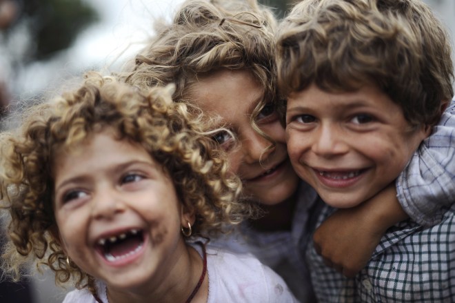 Roma children laugh in front of the came